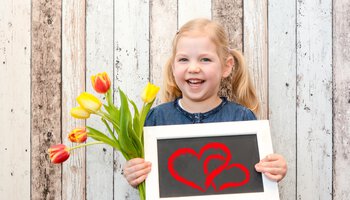 Kleines Mädchen hält Tulpen und Schild mit Herzen darauf | © Marco 2811 - Fotolia
