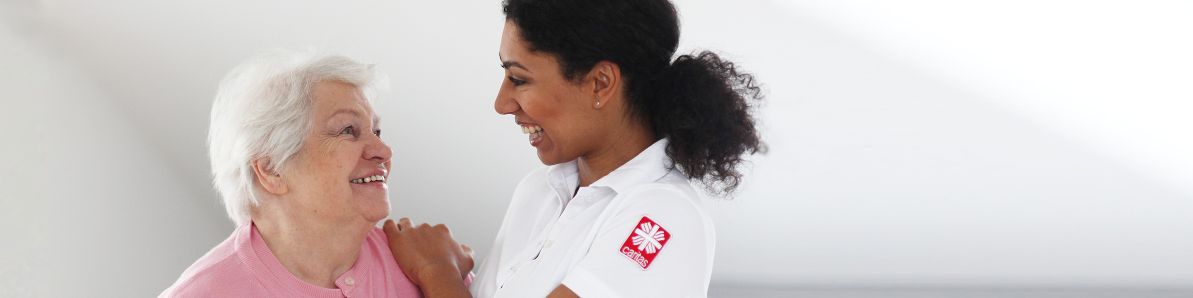 Eine Pflegerin legt eine Dame die Hand auf die Schulter | © Caritas München und Oberbayern