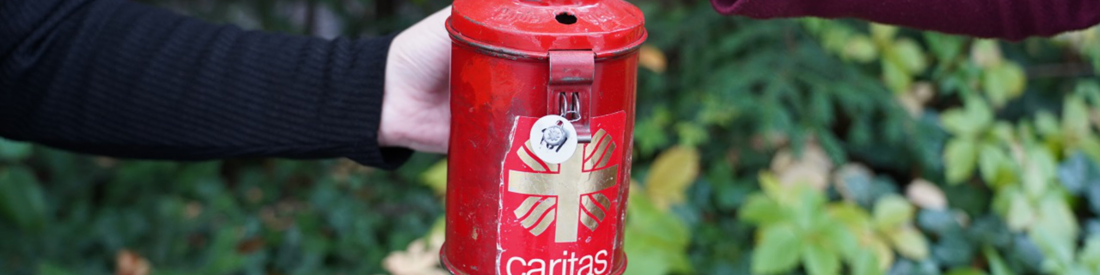 Münze wird in eine Caritas Spendensammelbüchse geworfen | © Caritas München Oberbayern